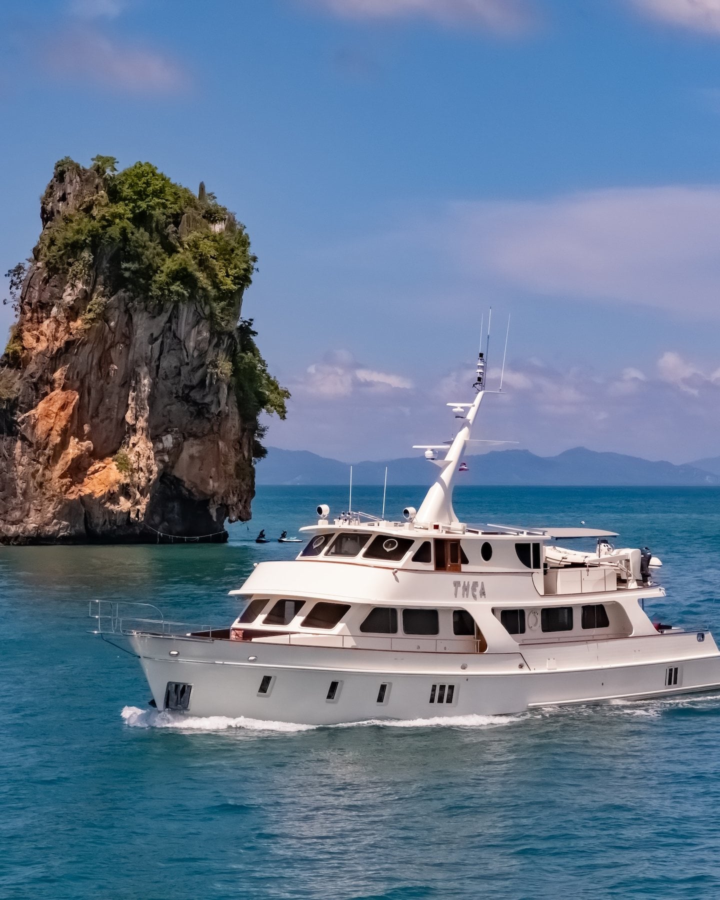 The white motor yacht THEA cruising past a limestone island in Phang Nga Bay