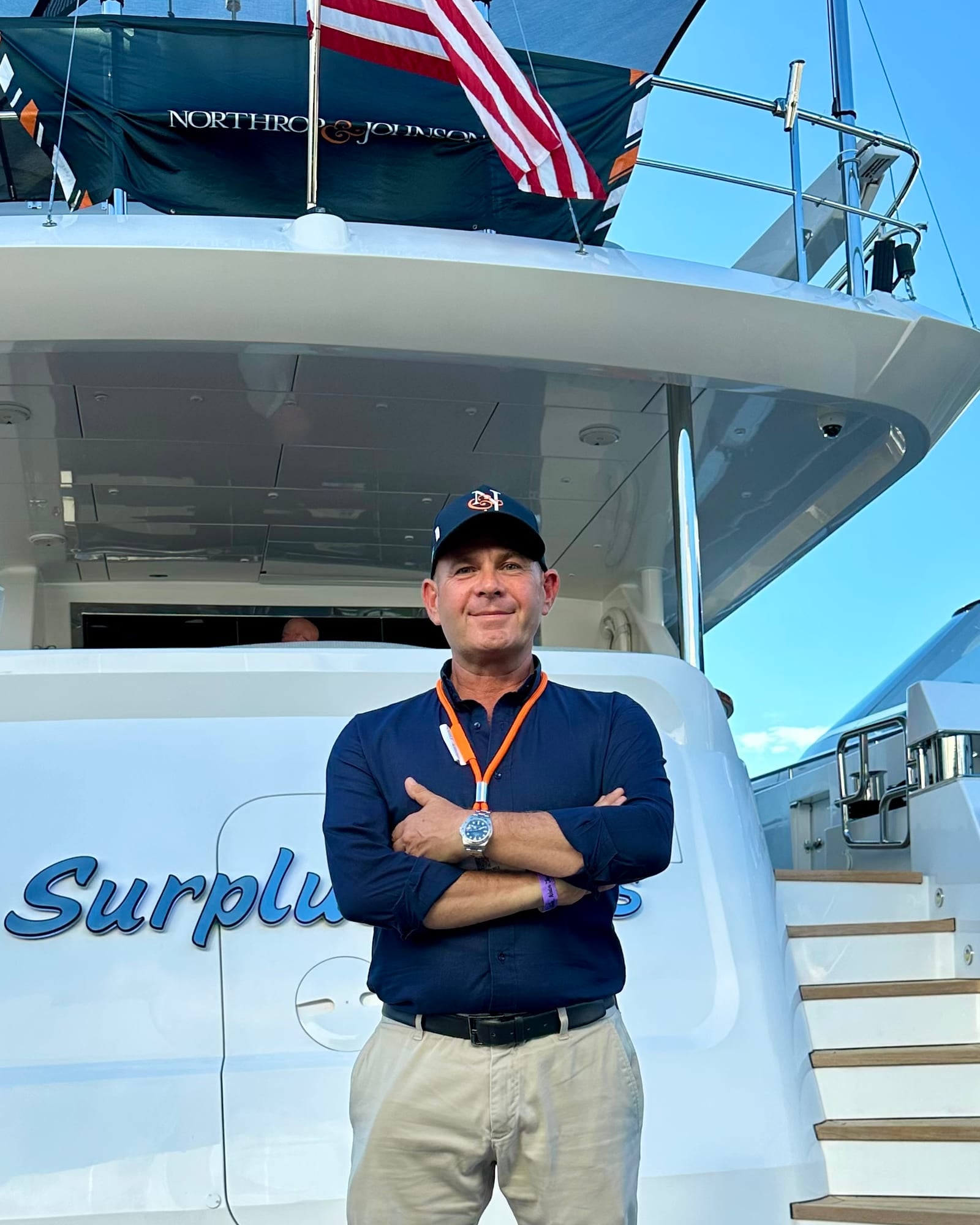 Martin Holmes, arms folded, at the stern of a motor yacht under a Northrop & Johnson banner